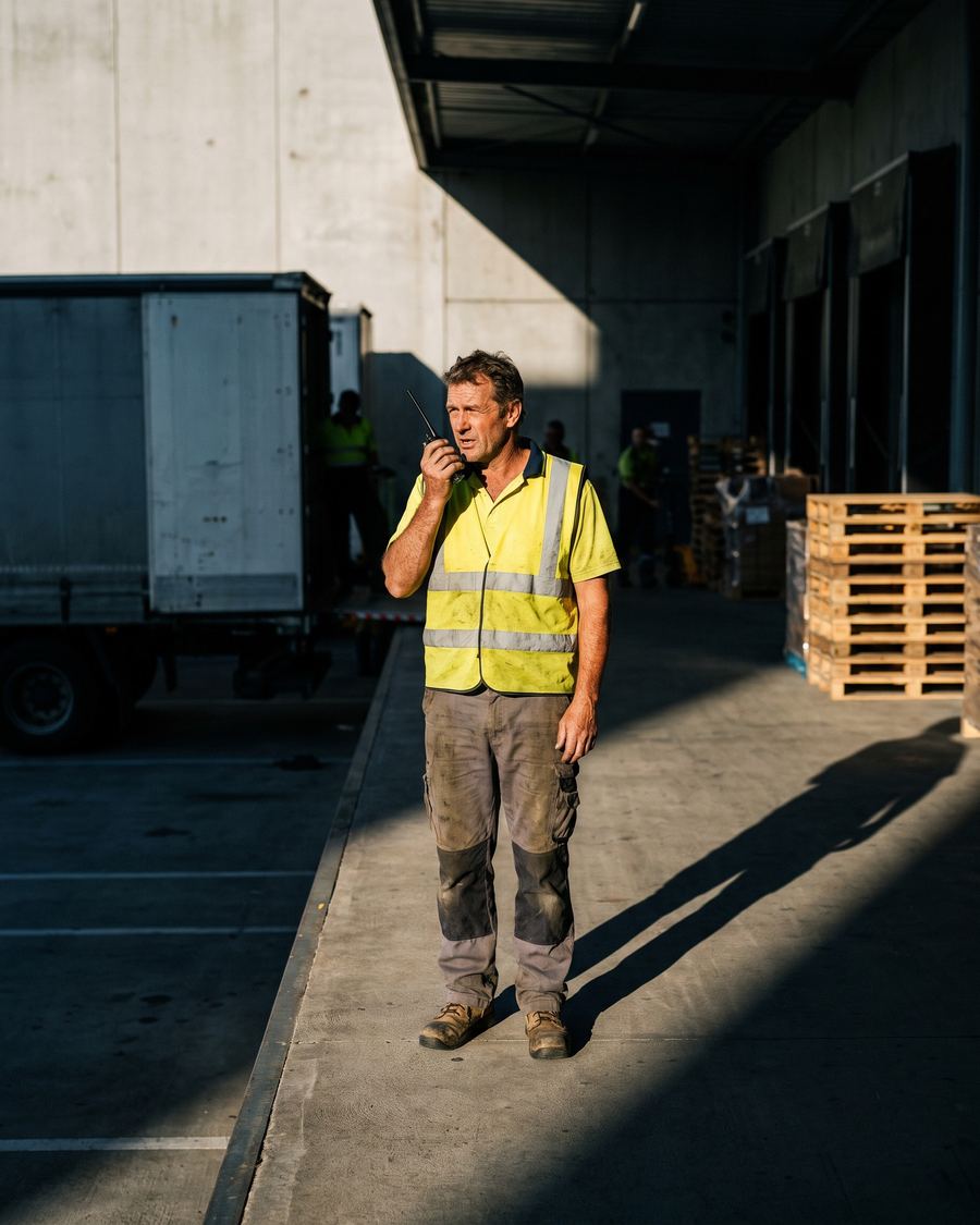 Supervisor con chaleco reflectivo hablando por radio en un muelle de carga